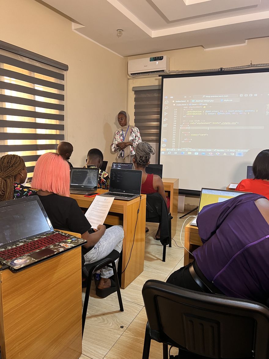 Tech Studio Academy instructor teaching a live coding class with code projected on screen and students following along on laptops